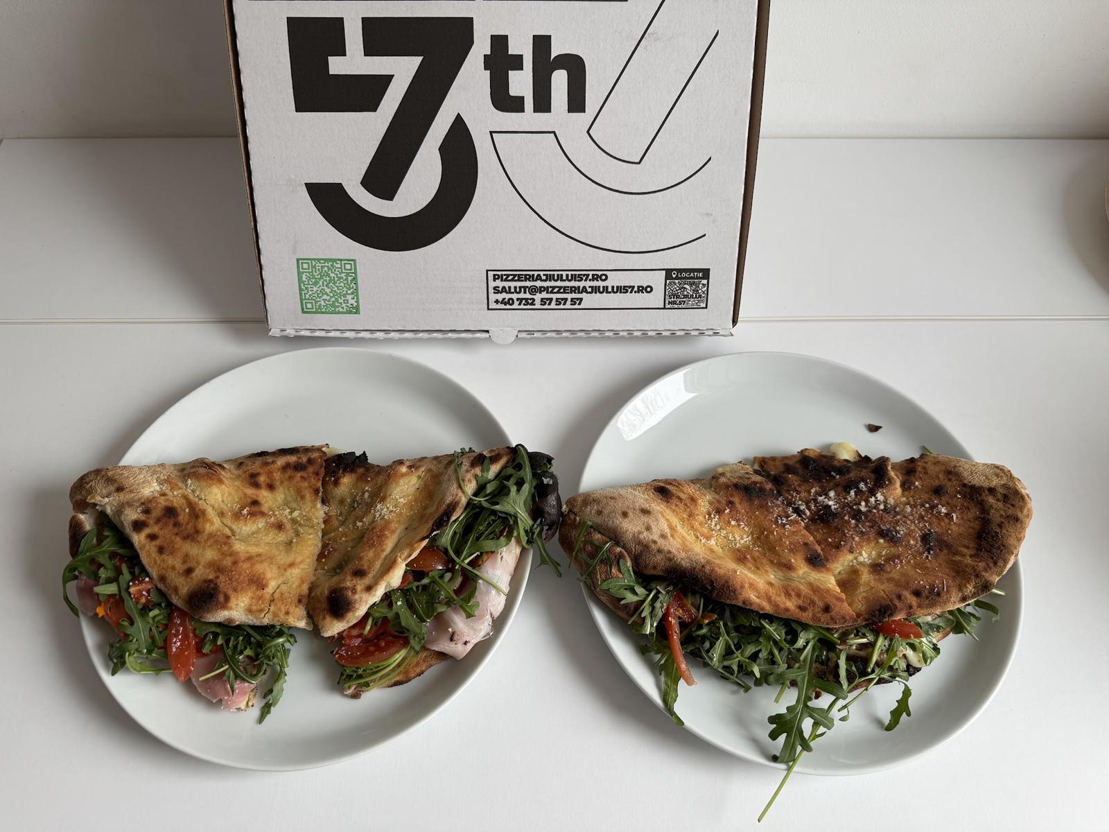 Două baciata pe farfurii, cu cutia Pizzeria 57 în spate
